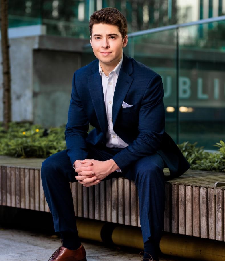 Man smiling at camera with hand together in buisness suit